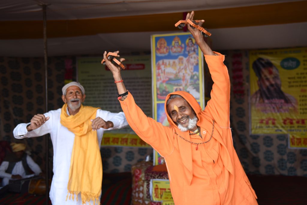 Two Hindu men dancing at the Kumbh Mela in Prayagraj, India, one of the amazing places in the world. (Image © Meredith Mullins.)