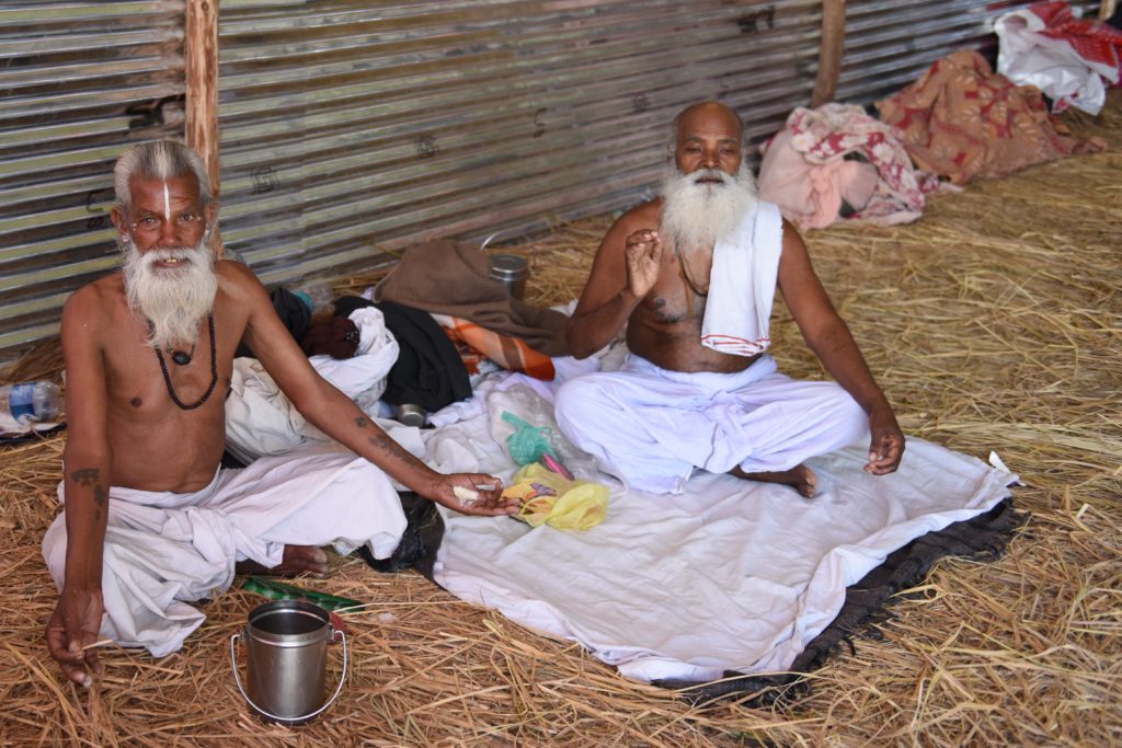 Two pilgrims in their temporary home at the 2019 Ardh Kumbh Mela in Prayagraj (Allahabad), India, one of the amazing places in the world. (Image © Meredith Mullins.)