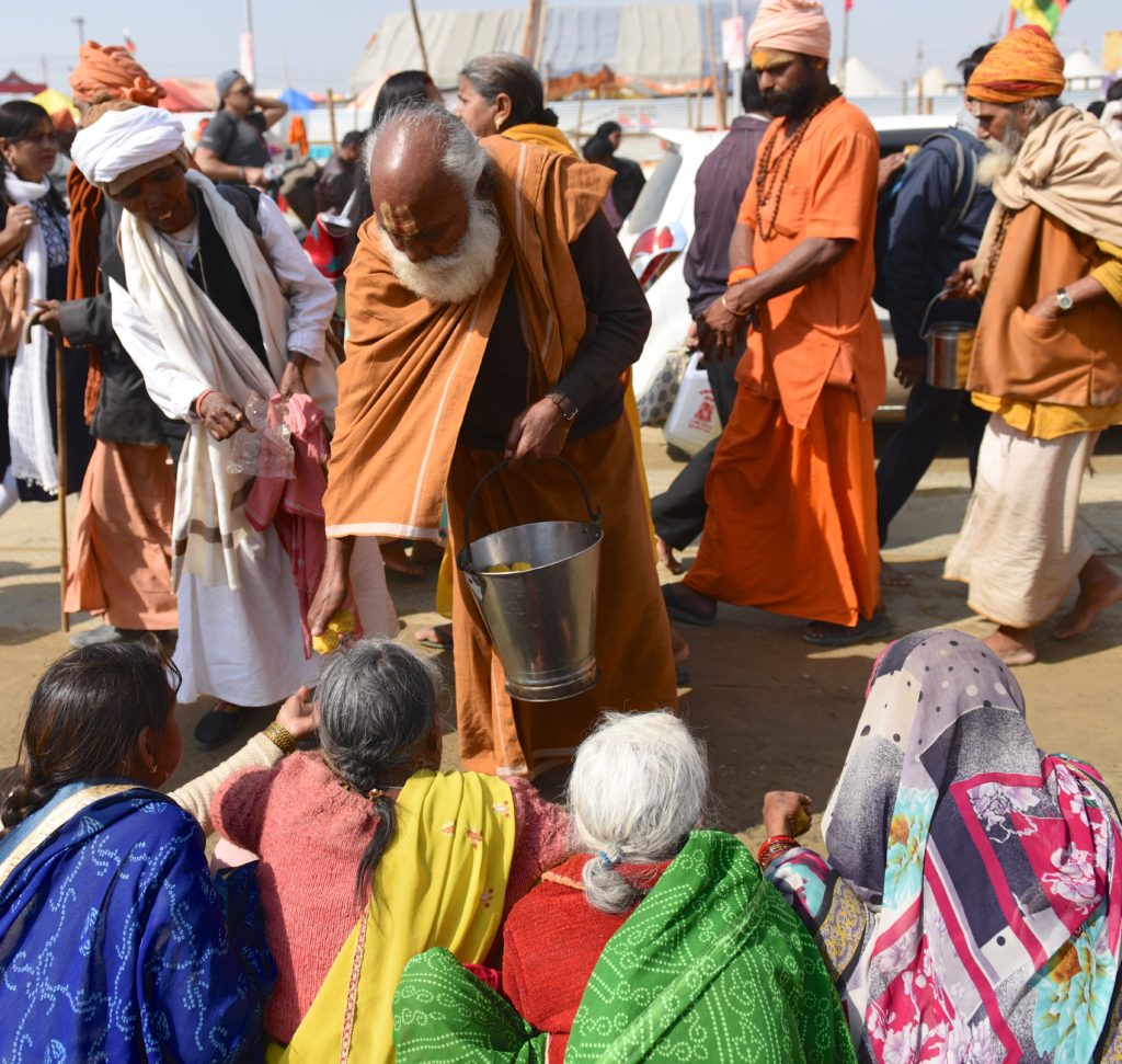 Man giving out food to the hungry at the 2019 Ardh Kumbh Mela in Prayagraj (Allahabad), India, one of the amazing places in the world. (Image © Meredith Mullins.)