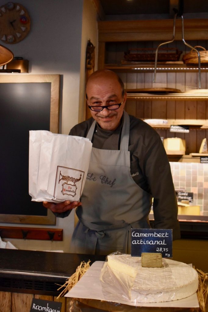 A Belgian cheesemonger saying hello shows that greeting is fundamental across cultures. (Image © Joyce McGreevy)