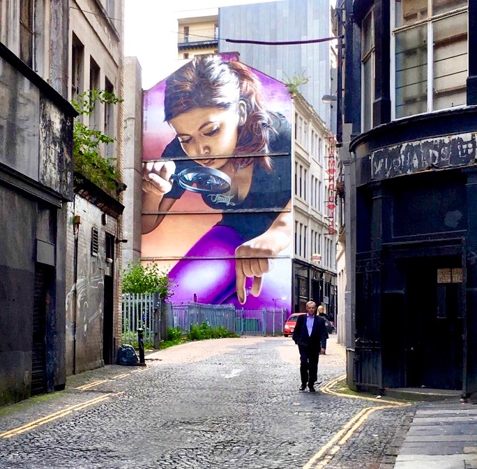 A mural in a street in Glasgow, Scotland shows why walking is a great way of seeing the world close up. (Image @ Joyce McGreevy)