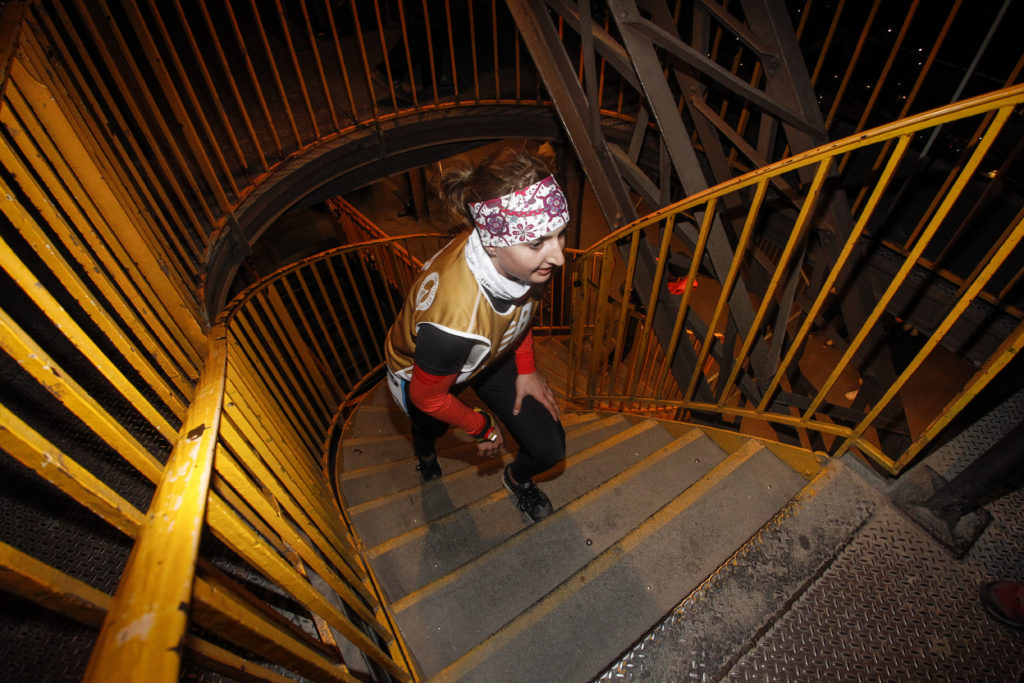 ECOTRAILORGA_CHRISTOPHEGUIARD, a woman running up stairs at the Eiffel Tower Vertical race at one of the amazing places on earth. (Image © EcoTrail Organization.) 