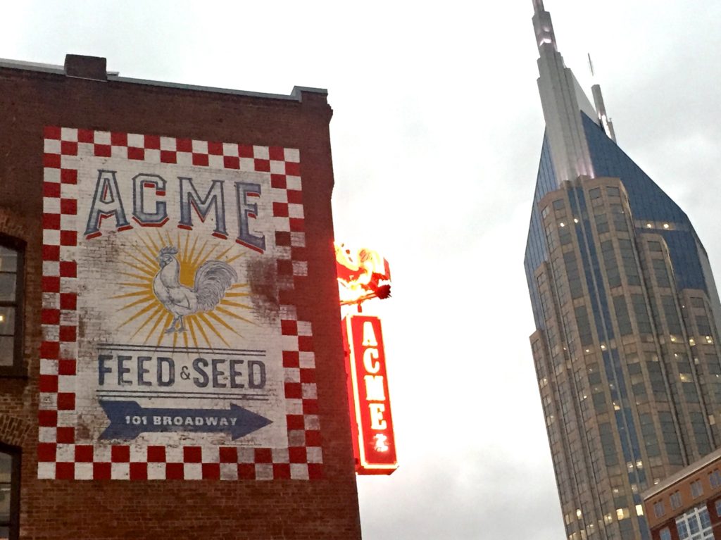 Acme Feed and skyscraper, a roadside sign of change, seen with the art of travel. (Image © Lauren Gezurian-Amlani.)