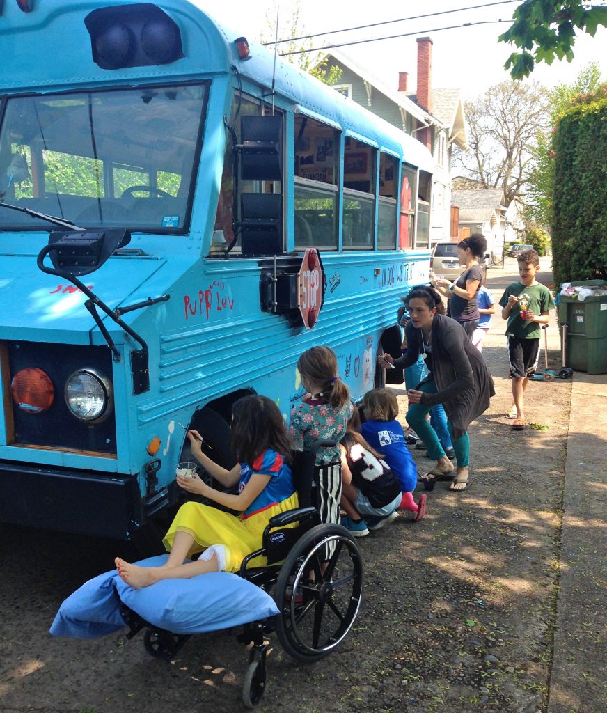 Families, children, and other creative thinkers paint the Dog Bus in Sullivan’s Gulch, Portland, Oregon. (Image © Meg Vogt)