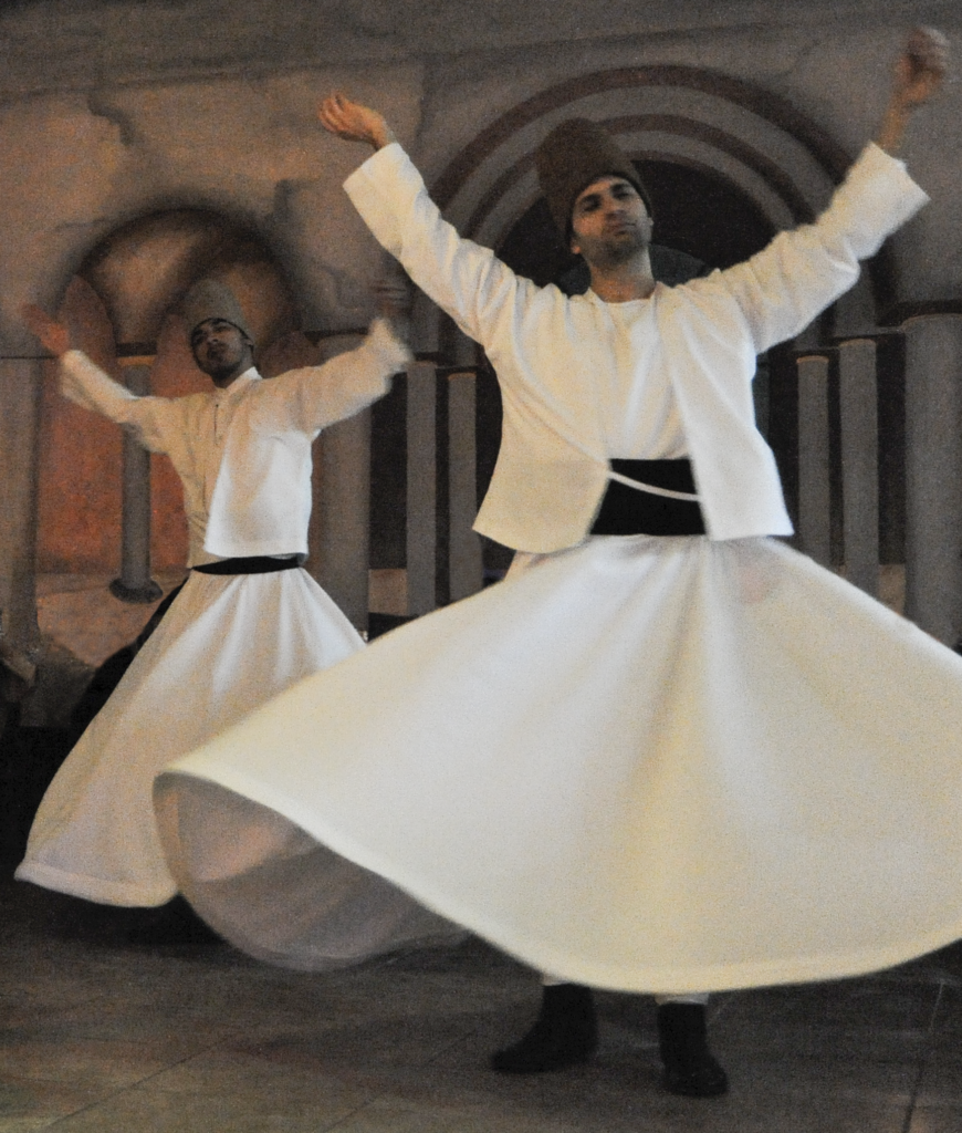 Two whirling dervishes dancing in Istanbul;s Sufi Sema ceremony. (Image © Meredith Mullins)