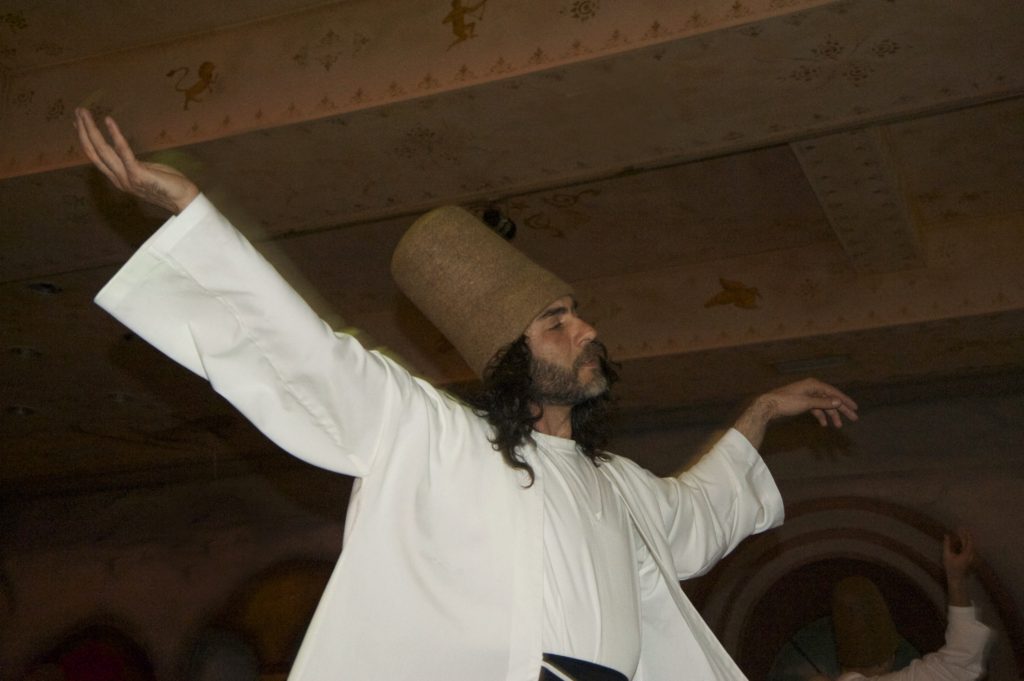 One of several whirling dervishes holding the palm of one hand toward the sky and the other hand toward Earth during the dance in the Sufi Sema ceremony in Istanbul. (Image © Meredith Mullins)