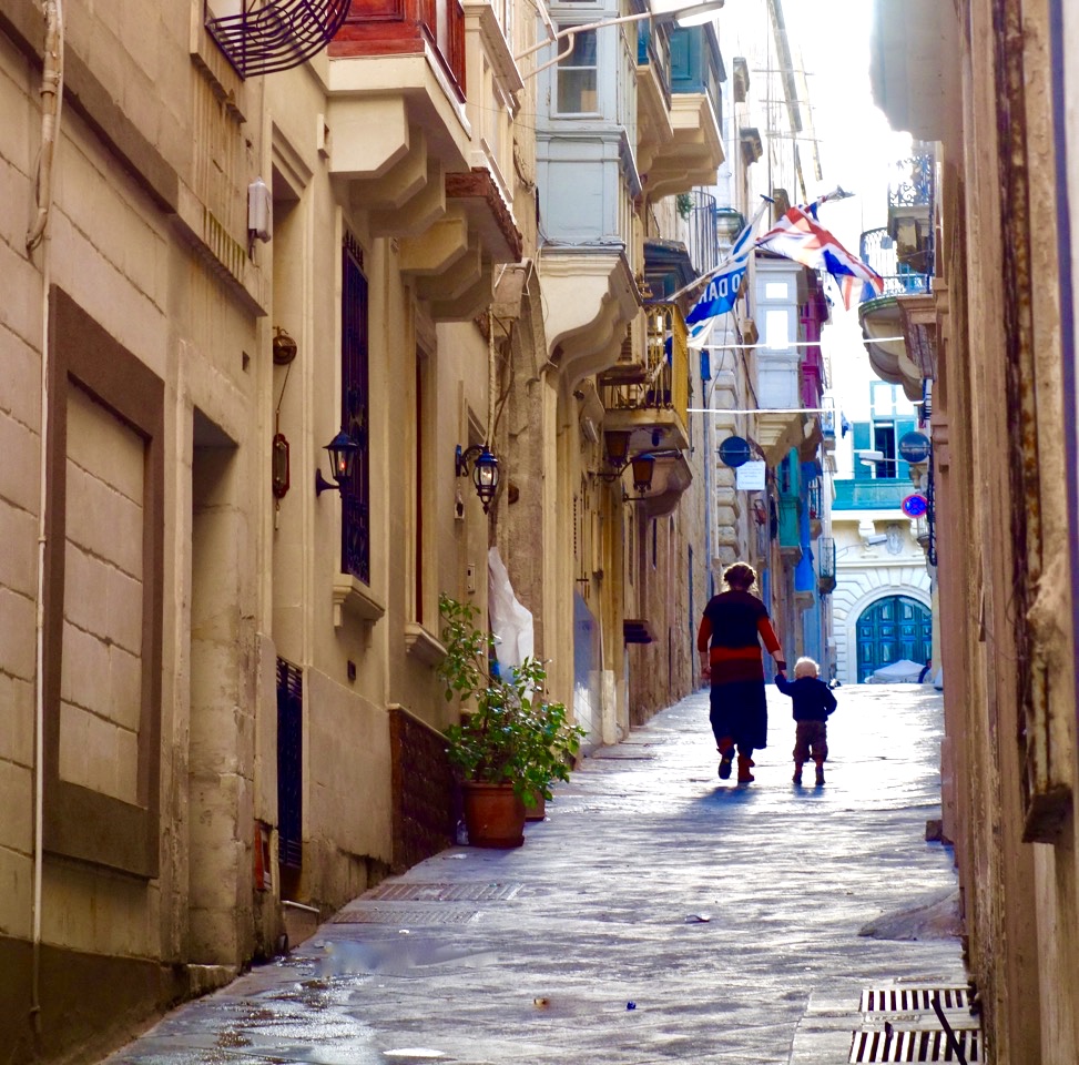 A mother and child walking home in Valletta, Malta evoke the domestic pleasures that make an art of travel as a digital nomad. (Image © Joyce McGreevy)
