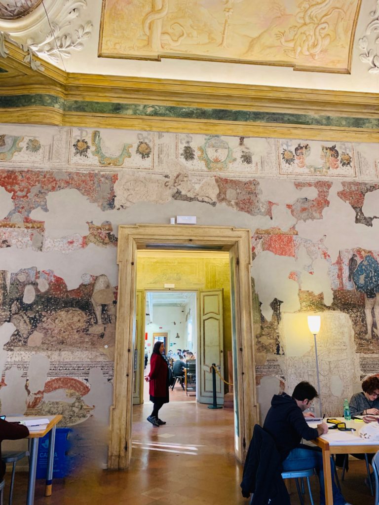 Frescoes on the walls of the Biblioteca Ariostea in Ferrara, Italy show why wanderlust leads travelers to public libraries, or library tourism, around the world. (Image © Joyce McGreevy)