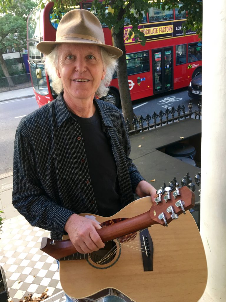 Rick Chelew, a musician from California in London, with his folding guitar, travels the world musically to connect across cultures. (Image © Joyce McGreevy)