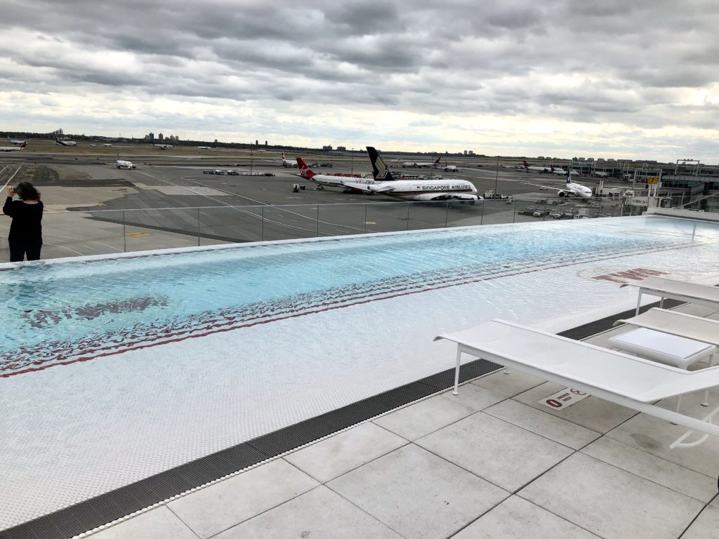 A TWA Hotel swimming pool with a view of the runway and airplanes evokes Trans World Airlines travel memories at JFK Airport, New York. (Image © Erin McGreevy Bevando)
