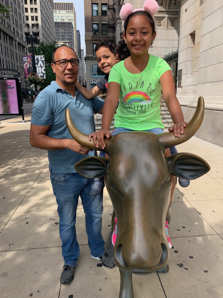 A family pose with the bronze cow sculpture at the Chicago Cultural Center, a popular attraction in the Conde Nast “Best Big City.” (Image © by Joyce McGreevy)