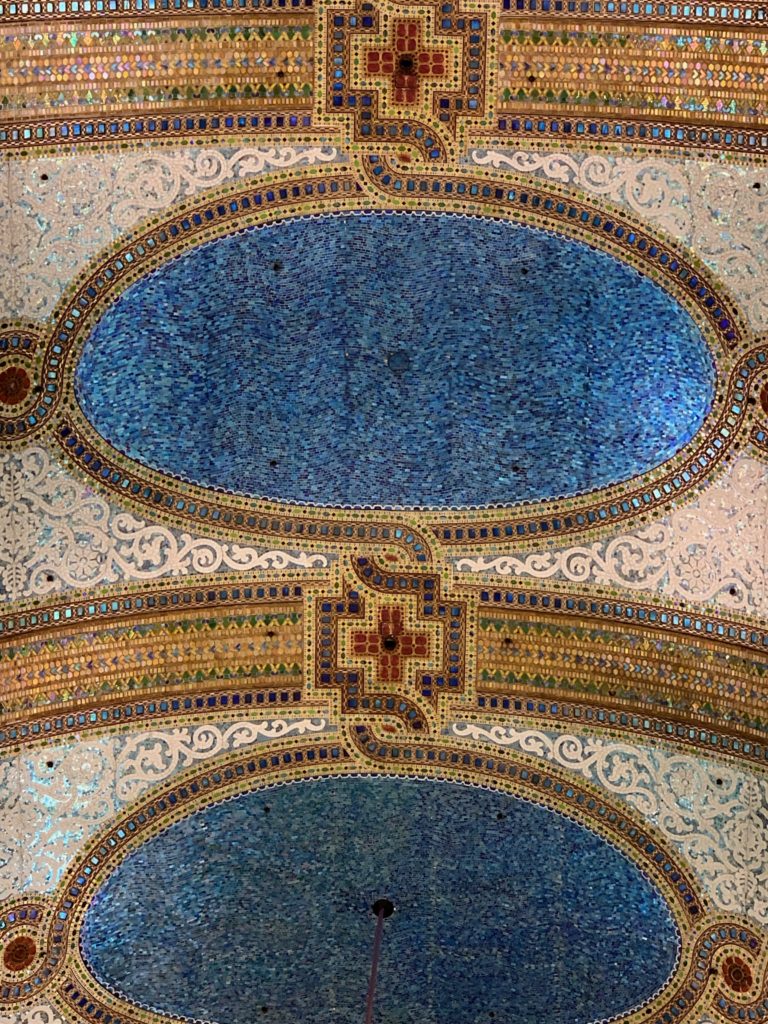 Little details of a mosaic by Louis Comfort Tiffany at the former Marshall Field, Chicago (now Macy’s) dazzles visitors who heed the travel tip “slow down and focus”. (Image © by Joyce McGreevy)