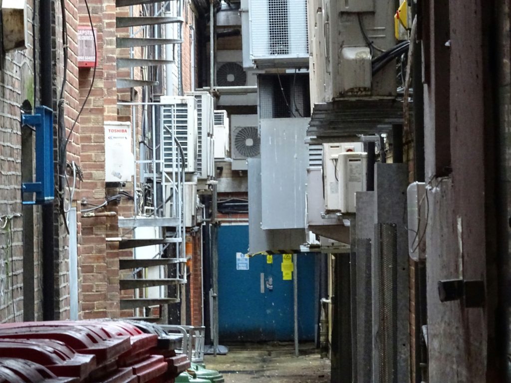 An urban alley cluttered with trash cans and utilities is a far cry from the green alleys and show the need for creative problem-solving. (Image © Alex Borland)