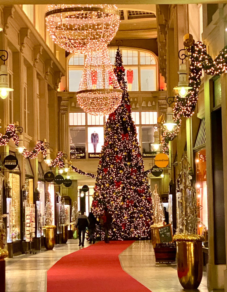 A Christmas tree in a red-carpeted, ornate passageway in Leipzig, Germany reflects one of the German Christmas traditions that inspire wanderlust for holiday travel. Image © Joyce McGreevy)