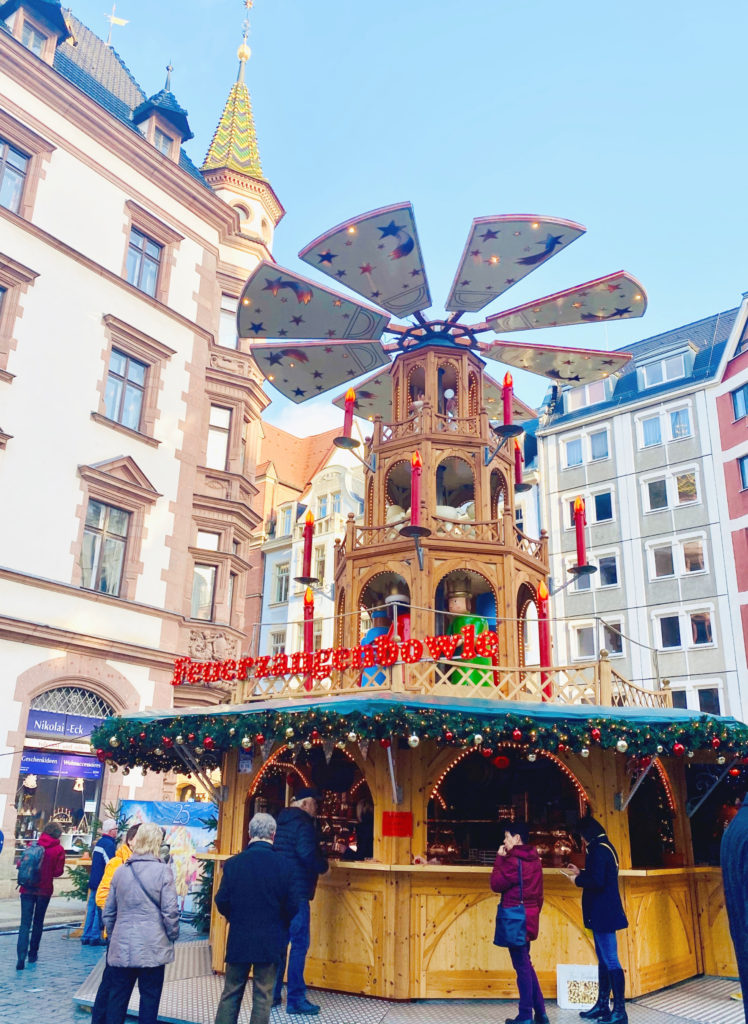 A giant Christmas pyramid, or Weihnachtspyramide, set against the beautiful architecture of Leipzig, Germany reflects a German Christmas tradition and inspires wanderlust for holiday travel. (Image © Joyce McGreevy)