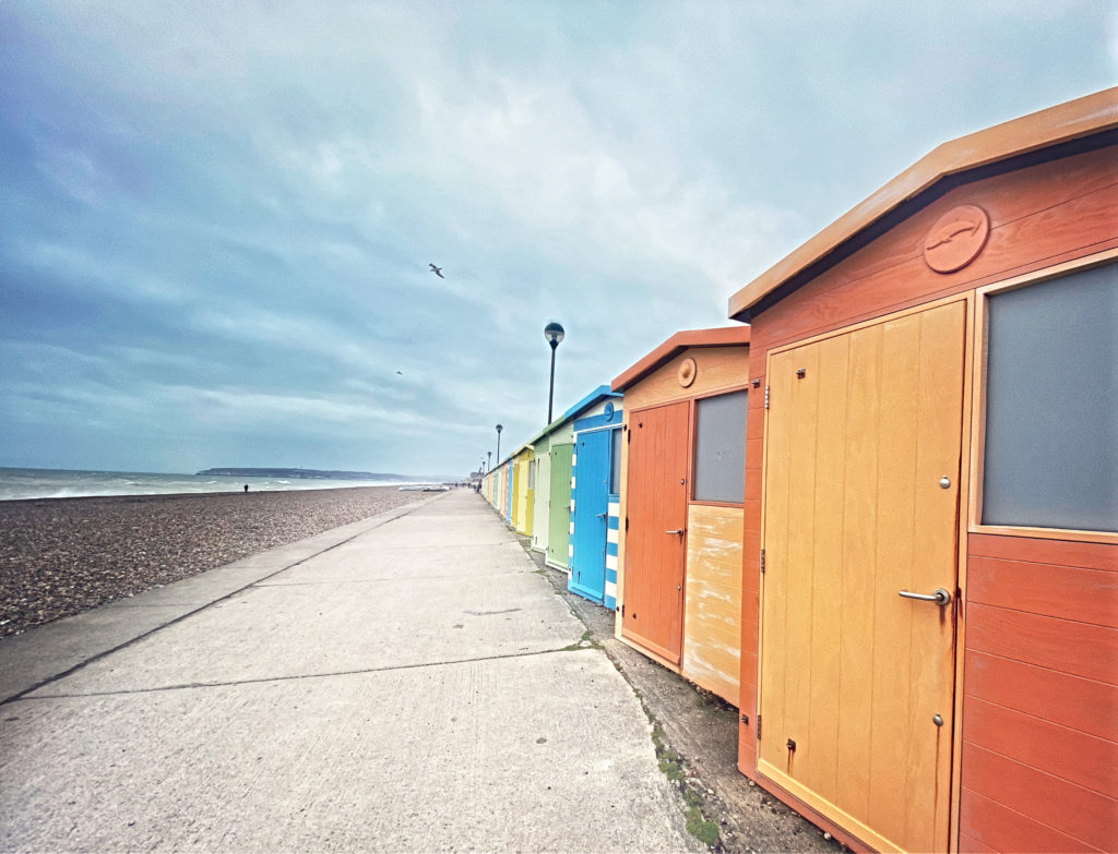 Traditional English beach huts on a deserts beach in East Sussex reminds a traveler with winter wanderlust that summer will return. (Image © Joyce McGreevy)