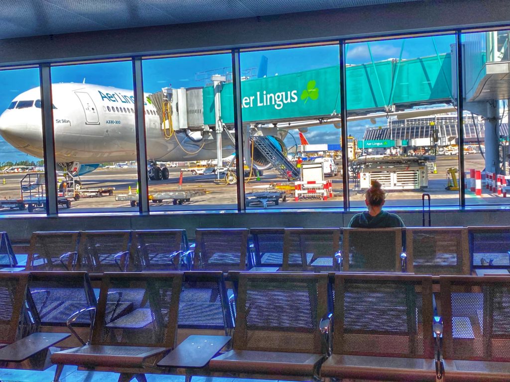 A lone airline passenger waits in the boarding area of an international airport during the pandemic. (Image © Joyce McGreevy)