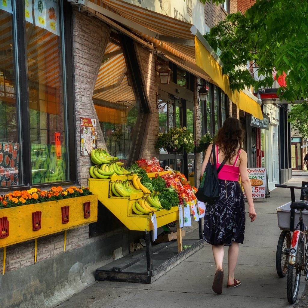 A woman walking and a corner grocery reflect the everyday pleasures of exploring Montréal’s urban culture. (Image © Joyce McGreevy)