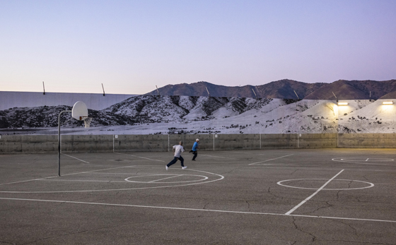 Artivist JR pastes a mural at the Tehachapi prison yard and wall, showing social awareness and answering the question can art change the world. (Image © JR.)