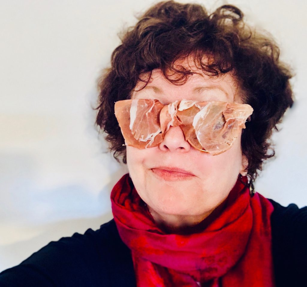 A woman looking through prosciutto-covered glasses views Italian wordplay and idioms from a unique perspective. (Image © Joyce McGreevy)