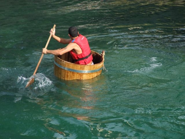 A man paddling a barrel in the water symbolizes how skeoumorph apps, with their cultural memory-based images of older physical objects, seemed clunky compared to Flat Design apps. (Image by Pxhere)