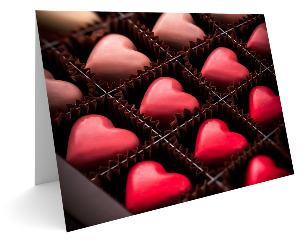 Heart-shaped candy in a candy box on a valentine card, part of the cultural traditions of Valentine's Day. image © Bojsha65/iStock