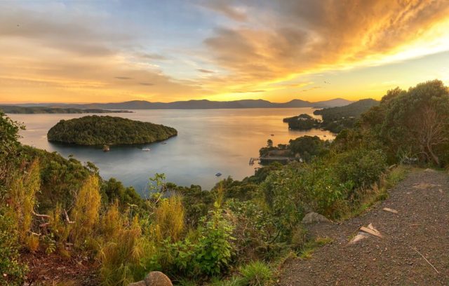 Sunset over Stewart Island, New Zealand inspires travel memories, during the epic wait for vaccines to make such journeys safe again. (Image © Joyce McGreevy)