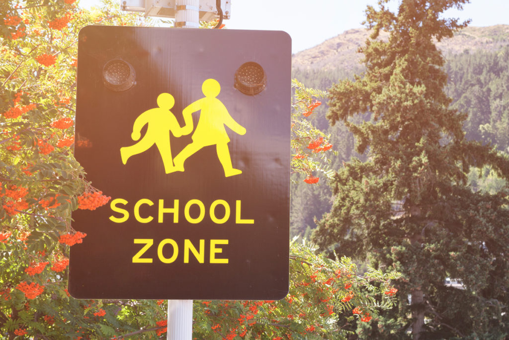 This school zone sign adopts a more realistic style, showing a girl and boy with hands and feet on their way to school, and is part of a series of school zone signs from different cultures. Image © Powerofforever/iStock .