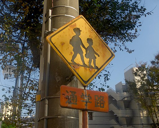 This school zone sign in Japan features two students wearing caps, one a boy in short pants and the other a girl in a pleated skirt, both part of the traditional uniforms for elementary students, and is part of a series of school zone signs from different cultures. <br>Image courtesy of Nesnad, CC BY 3.0 via Wikimedia Commons