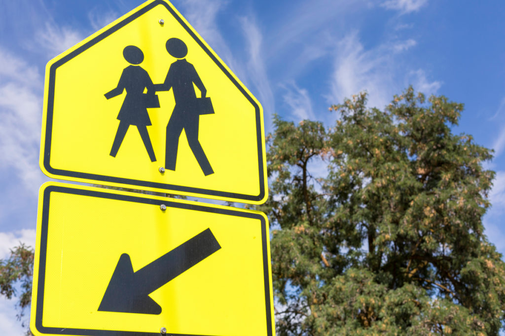 This yellow-green fluorescent school zone sign and arrow from the USA with a female and male student holding a book is part of a series of school zone signs from different cultures. Image © Garrett Aitken/iStock. 