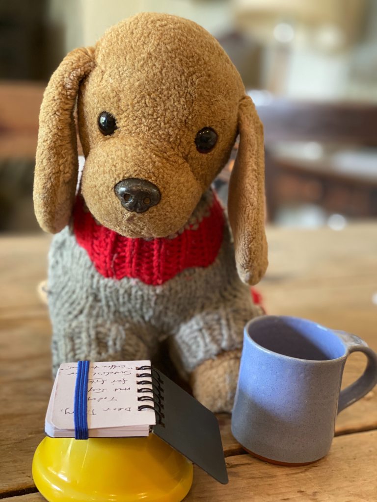 A toy dog sharing Swedish fika shows that a sense of play and cross-cultural tips help one stay calm when sheltering in place during the pandemic. (Image © Joyce McGreevy)