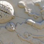 Sandstone carving showing people being puled through the air by balloons in the shape of a brain, symbolizing the boosting power of being bilingual and culturally competent across different cultures. (Image © FotoEmotions/Pixabay) 