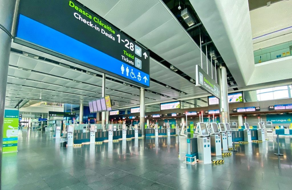 Airline check-in kiosks at Dublin International Airport during the pandemic stand idle, as the author contemplates flying “on a wing and dare.” (Image © Joyce McGreevy)