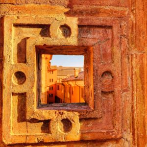 A stone window in Ferrara, Italy reminds the author that wanderlust for Italy and a well-organized travel plan for a trip to Italy can inspire a whole new perspective on the world. (Image © by Joyce McGreevy)